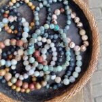 Vertical close up of art in the everyday: earth color crystal bracelets in wicker and stone basket at artisan markets Byron Bay